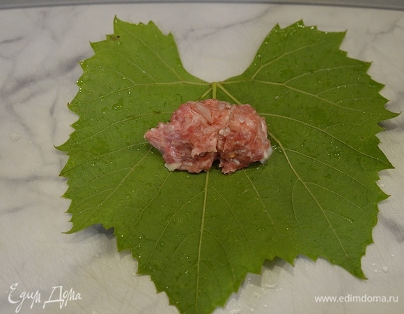 На матовую сторону виноградного листа выкладывайте немного фарша.