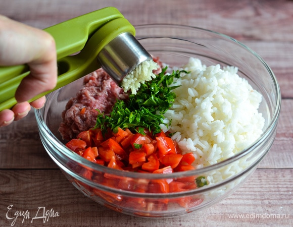 Рис отварить до готовности, остудить. Томаты нарезать мелким кубиком. Петрушку мелко порубить. Чеснок выдавить через пресс. Соединить все с фаршем.