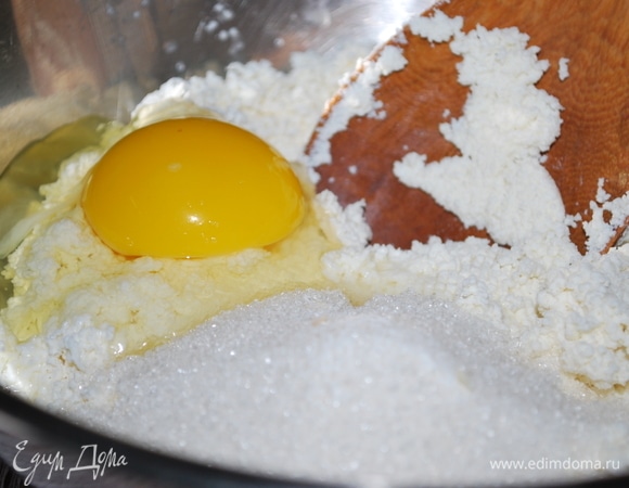 Выложите протертый творог в миску. Добавьте куриное яйцо, сахар, ванильный сахар по вкусу и соль, хорошо перемешайте.