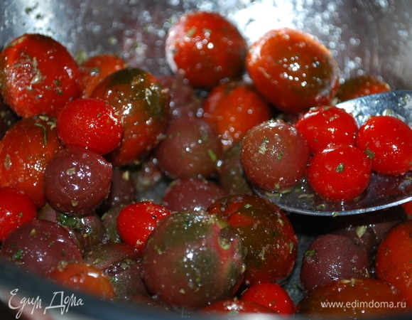 В миску выложите помидоры черри, выдавите с помощью пресса зубчик чеснока. Добавьте сухие ароматные травы, соль, свежемолотый черный перец, свежий базилик и оливковое масло. Все хорошо перемешайте.