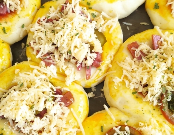 Выкладываем на противень (я выложила на пергамент, смазанный маслом) и оставляем минут на 15 для поднятия. Делаем небольшие пиццы, смазываем соусом, кладем начинку и сыр, смазываем яйцом по бокам и запекаем до румяной корочки при 180°C. Приятного аппетита!