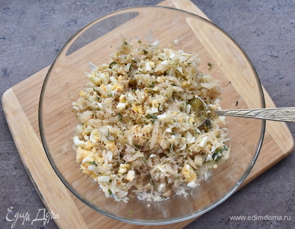 Пока тесто подходит, подготавливаю начинку. Капусту мелко шинкую, лук нарезаю кубиком и пассерую все на растительном масле. Накрываю сковороду крышкой и томлю капусту еще 7–10 минут на медленном огне. Солю, перчу, добавляю рубленую зелень, яйца и зеленый лук. Начинку перекладываю в миску и остужаю.