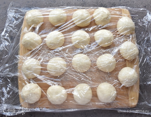 Подошедшее тесто делю на кусочки весом 45–47 г (19 штук). Скатываю тесто в шарики и накрываю пищевой пленкой, чтобы не заветрились.