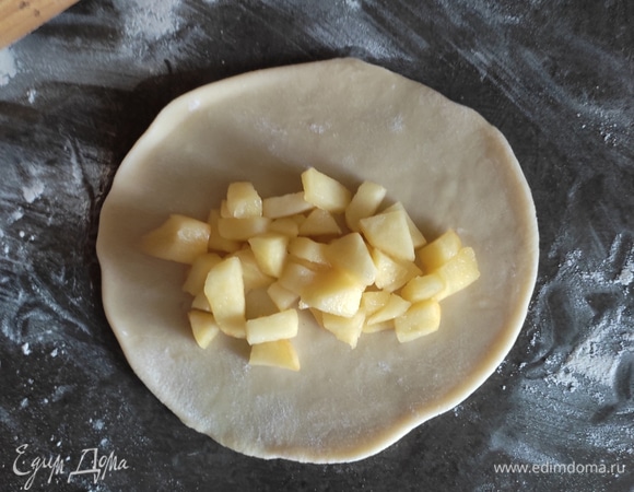 Подошедшее тесто делим на 8 одинаковых частей (я это делаю с помощью весов). Каждый кусочек округляем и оставляем под пленкой еще на 10 минут. После чего берем шарик, раскатываем в лепешку диаметром около 15 см, на середину выкладываем начинку.