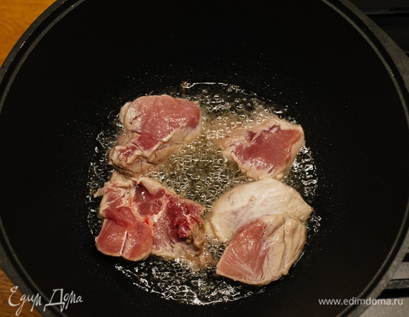 Положить мясо в казан и обжарить до румяности на сильном огне.