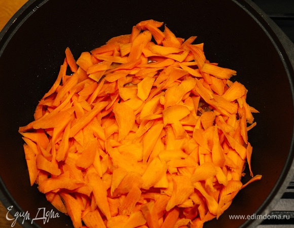 Через минут 5 положить в казан морковь, нашинкованную крупной стружкой.