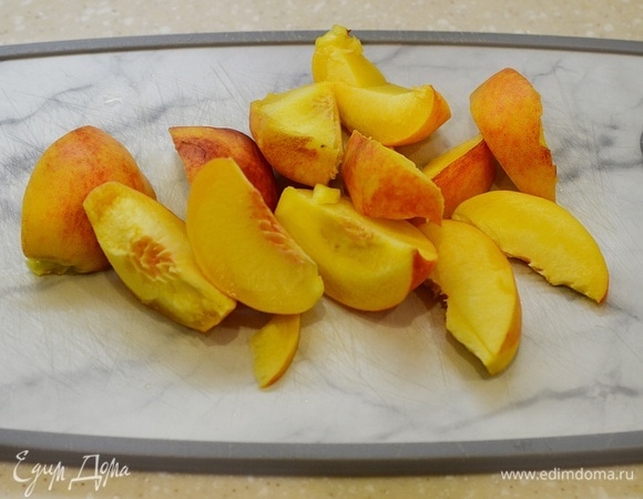 Персики вымойте, удалите косточки и нарежьте дольками.