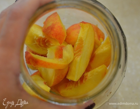 В стерилизованные банки положите персики. Они должны заполнить емкость на 1/3.