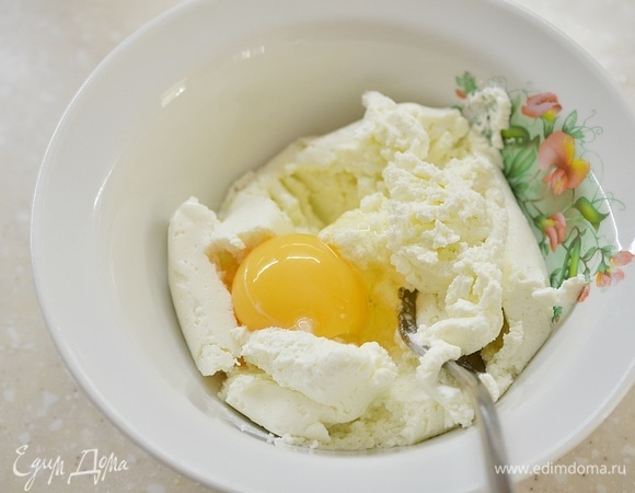 Творог разомните вилкой, добавьте желток и перемешайте.