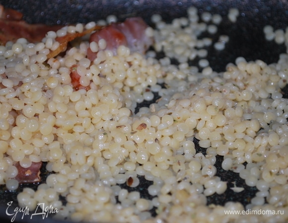 Птитим предварительно отварите до состояния альденте, посолите по вкусу. Готовые макаронные изделия откиньте на дуршлаг, чтобы стекла вода, и добавьте ее в сковороду к обжаренному бекону. Перемешайте, паста пропитается ароматом бекона и орегано.