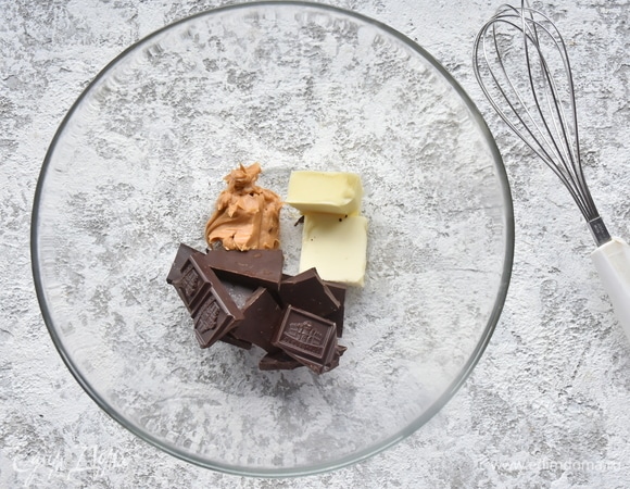 Соединить в миске шоколад, масло сливочное и арахисовую пасту. Растопить на водяной бане или импульсами в микроволновой печи. Перемешать смесь до однородности.