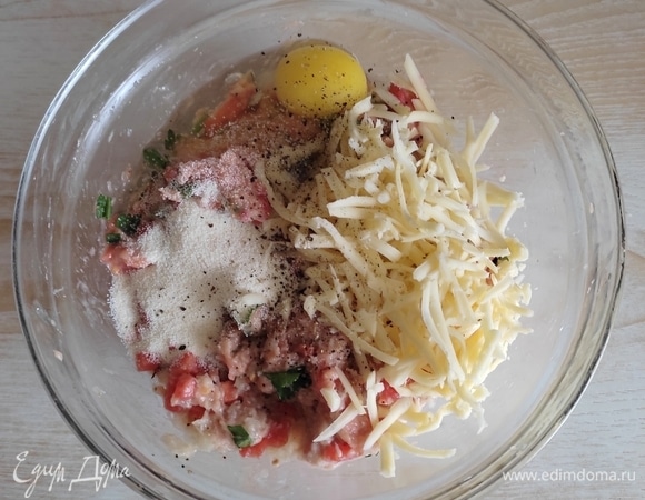 В чашу сложить фарш, зелень, кубики помидора, сыр. Добавить манную крупу, специи, посолить по вкусу.