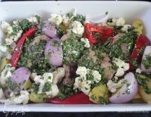 В форму с курицей выложить овощи и щедро смазать все зеленым соусом. Уменьшить температуру до 180°C и запекать все еще 30–35 минут.