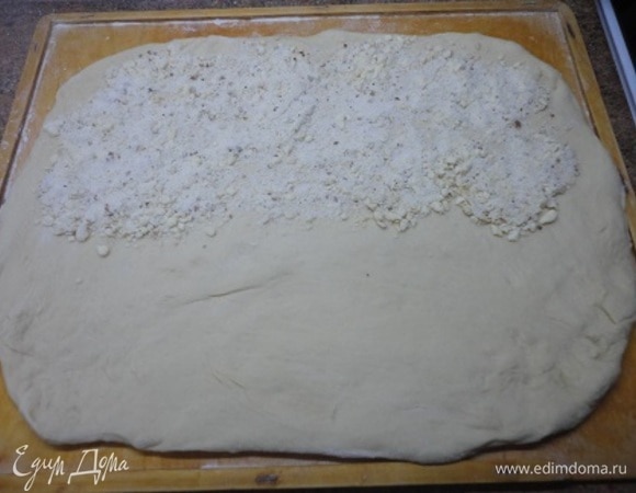 Тесто разделить на две части и каждую раскатать в прямоугольник толщиной в 1 см. На половину прямоугольника высыпать часть крошки, накрыть второй половиной и слегка раскатать. Вновь равномерно посыпать на половину заготовки крошку, снова сложить пополам и раскатать. Повторить все еще раз. Это же проделываем и со второй частью теста. Можно оставить немного крошки для финальной посыпки.