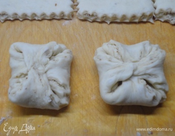 Противоположные концы квадрата соединить между собой. Выложить на противень и оставить на расстойку. Включить духовку для разогрева на 180°C. Подошедшие изделия смазать желтком и посыпать ореховым штрейзелем.
