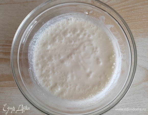 Кефир лучше брать не слишком свежий, идеально подойдет тот, которому 4–5 дней, тогда оладьи получатся более пышными. Выливаем в чашу, перемешиваем венчиком и ставим в микроволновку, подогреваем до очень теплого, почти горячего состояния (можно подогреть на плите).