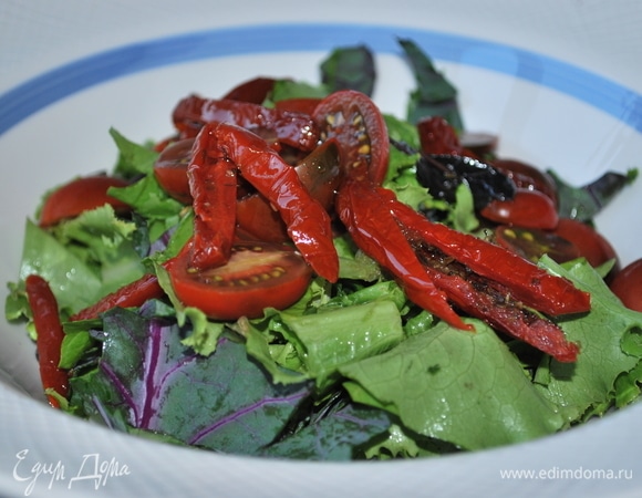 Помидоры черри разрежьте пополам. Выложите салат, вяленые помидоры и томаты черри в большую миску. Посолите и поперчите по вкусу, добавьте оливковое масло, перемешайте.
