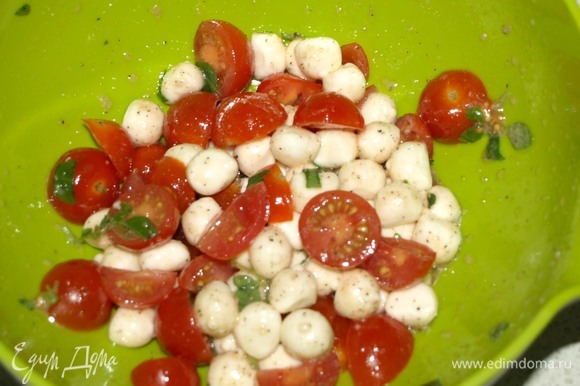 Помидоры черри разрезать на 2 или 4 части. Соединить в миске мини-моцареллу, томаты, мелко нарезанный зеленый базилик, соль, перец и оливковое масло. Перемешать.