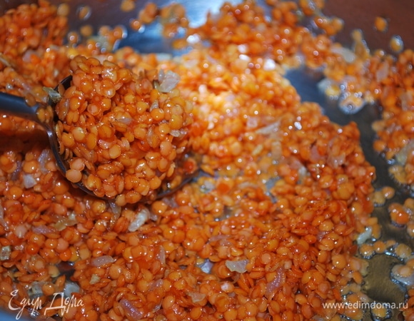 К обжаренному луку добавьте красную чечевицу и прогрейте все вместе в течение 2–3 минут.