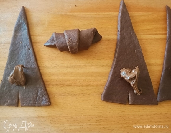 На каждый треугольник выложить по 1 ч. л. шоколадной пасты и аккуратно свернуть к меньшему краю, как бы наматывая тесто.