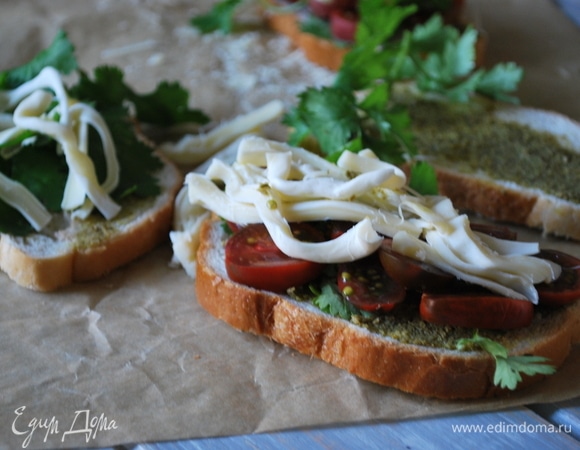 На соус песто выложите свежую зелень, нарезанные помидоры черри и кусочки сыра.