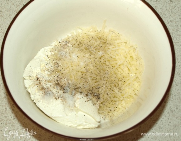 Твердый сыр натереть на мелкой терке. Смешать в миске творожный соленый сыр, твердый сыр, черный молотый перец и соль по вкусу.