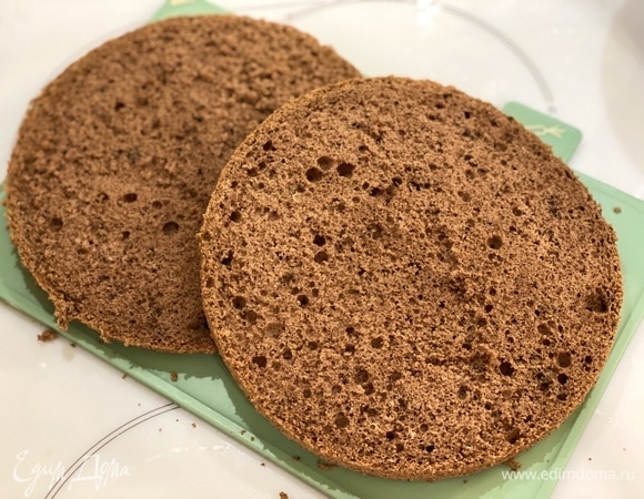 Приготовим бисквит. Яйца взбивать с сахаром, пока масса не увеличится в объеме и не побелеет. Муку, крахмал, какао и разрыхлитель просеять в яичную смесь в 3 приема. Аккуратными движениями снизу вверх замесить тесто. Тесто вылить в форму, застеленную пергаментом. Выпекать примерно 40 минут при 150°C, до пробы на сухую палочку. Готовый бисквит остудить на решетке, вынув из формы, и разрезать на 2 равных коржа.