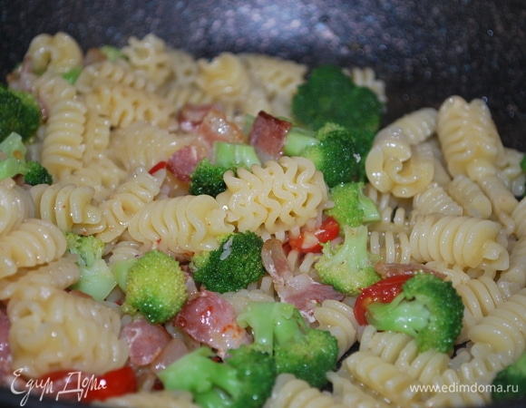 В сковороду к бекону с помидорами добавьте макароны с брокколи, посыпьте орегано по вкусу, перемешайте.