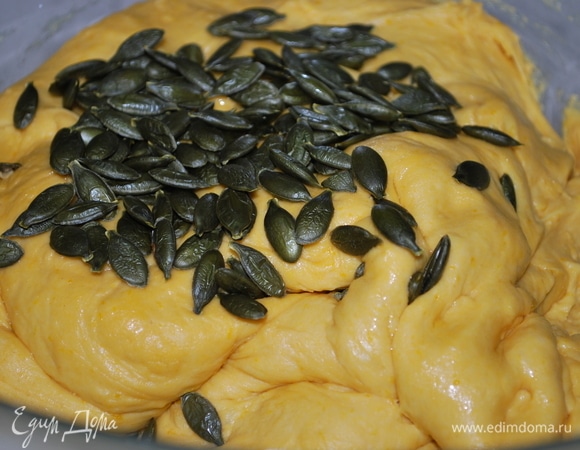 Примерно через 2 часа в тесто добавьте обжаренные тыквенные семечки, смешайте.