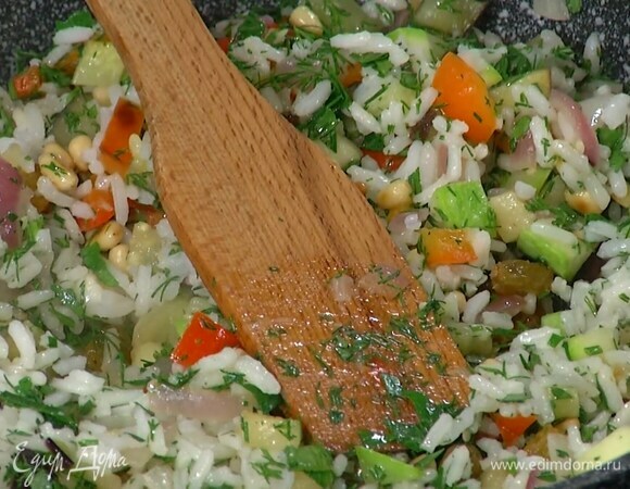 Отваренный рис выложить в сковороду с овощами, добавить орехи с изюмом и измельченную зелень, все перемешать и немного прогреть. 