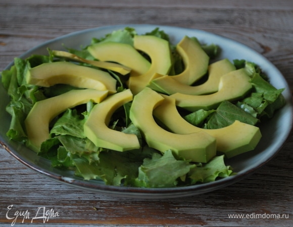 Салатные листья вымойте, крупно нарежьте и выложите на тарелку. Авокадо почистите, удалите косточку, нарежьте дольками и выложите сверху на салатные листья.