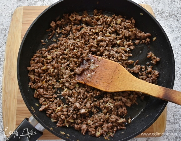 В сковороде разогреваю растительное масло. Обжариваю нарезанный кубиком репчатый лук. Добавляю фарш, сухой базилик и обжариваю с луком, разбивая мясные комочки деревянной лопаткой. Солю, перчу.
