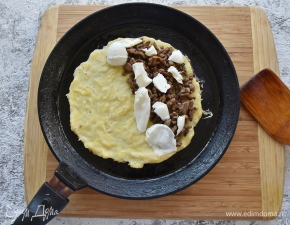 Блинную сковороду смазываю небольшим количеством растительного масла. Выкладываю часть кабачкового теста (примерно 3 ст. л.) и распределяю его тонким слоем в форме круглого блинчика. На половину блина выкладываю часть мясного фарша и кусочки моцареллы.