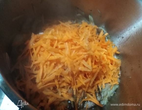 В кастрюлю выложить натертую морковь. Жарить до изменения цвета.