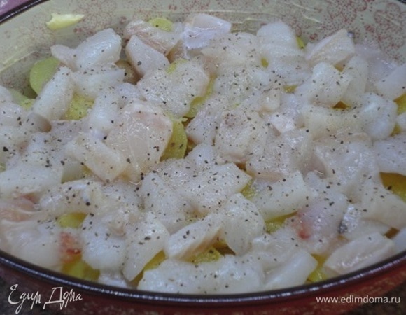 Рыбу вымыть и обсушить кухонным полотенцем. Нарезать кубиками размером примерно 3х3 см, посолить, поперчить и перемешать. Форму для запекания смазать сливочным маслом. На дно выложить половину картофеля, сверху — половину рыбы.