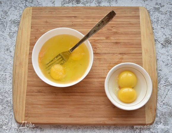 В миске соединяю 2 целых яйца и 2 белка, перемешиваю вилкой. Оставшиеся пару желтков отделяю и откладываю в сторону. К яйцам добавляю соль, перец, обжаренную ветчину с беконом и тертый сыр.