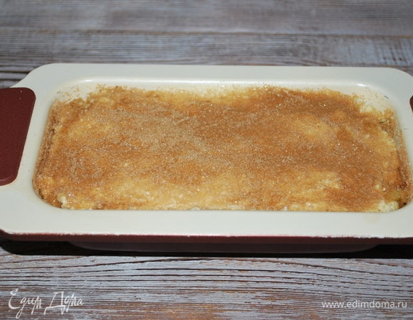 На яблоки — оставшееся тесто. Разровняйте поверхность заготовки с помощью лопатки. Верх пирога посыпьте сахаром с корицей. Выпекайте при 170°C примерно 40 минут, до готовности.