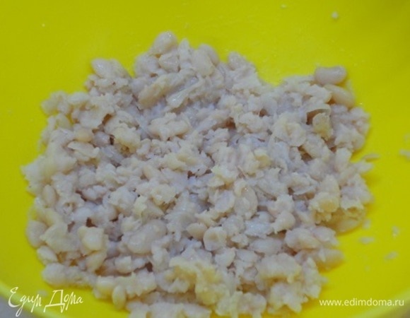 Готовую фасоль откинуть на дуршлаг и слегка размять толкушкой.