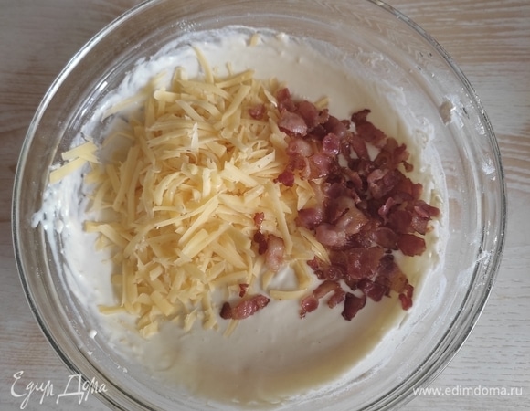 В готовое тесто добавляем тертый сыр и бекон, аккуратно перемешиваем. Оставьте немного бекона для украшения кексов.