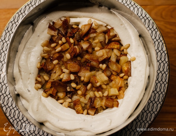 Для начала необходимо сделать из крема борт на бисквите. Затем выложить половину грушевой начинки и посыпать кедровыми орешками.