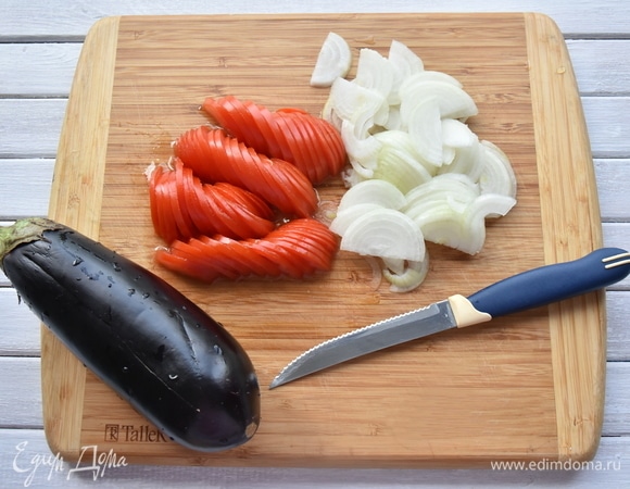 Баклажаны очищаю от чашелистиков, оставив хвостики. Снимаю ножом или овощечисткой несколько полосок кожуры с баклажанов. Делаю продольный надрез до середины овоща, отступив от концов по 2 см. Слегка солю мякоть и оставляю на некоторое время. Отжимаю лишнюю жидкость и обсушиваю. Нарезаю полукольцами томаты и лук. Зелень и чеснок измельчаю.