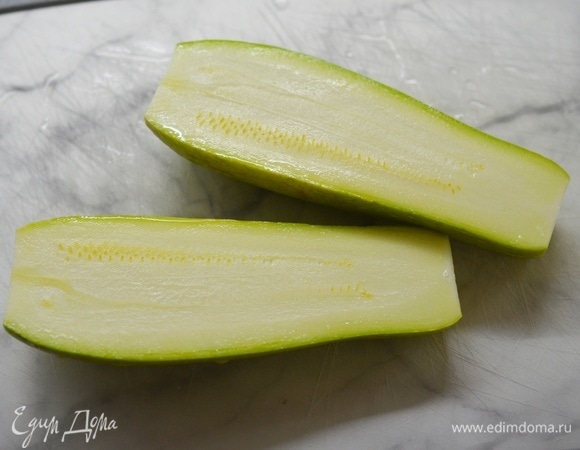 У кабачка отрежьте плодоножку и разрежьте вдоль пополам.