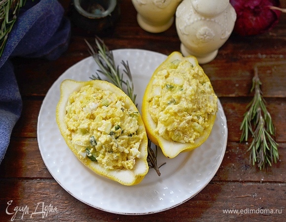 Выложите салат в лимонные половинки и подавайте к столу.