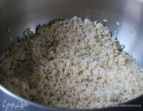 В сотейнике с толстым дном разогрейте сливочное масло. На небольшом огне обжарьте чеснок и рис до появления легкого аромата, в течение 2–3 минут.