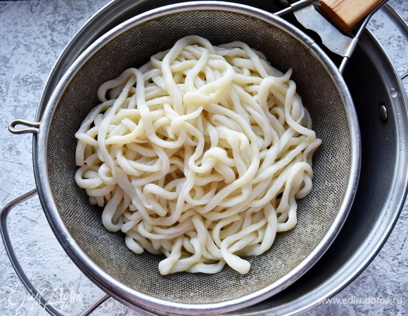 Довожу подсоленную воду до кипения и перекладываю в нее подготовленную лапшу. Варю 8–10 минут. Готовую лапшу откидываю на сито и опускаю в холодную воду на несколько секунд, после чего даю стечь лишней жидкости.