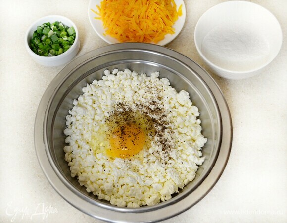 Зеленый лук вымыть, просушить и мелко нарезать. Сыр натрите на крупной терке. Яйца взбить венчиком с солью и сахаром. Добавить творог, часть немного размять ложкой или вилкой, приправить перцем, добавить измельченный лук и сыр. Перемешать. Частями ввести рисовую муку, перемешать и, если позволяет время, поставить емкость с получившейся массой на 30 мин в холодильник.