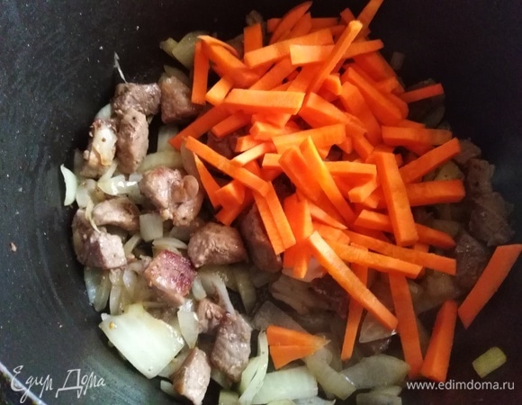 Всыпать репчатый лук, слегка припустить с мясом. Добавить нарезанную брусочками морковь. Обжарить.