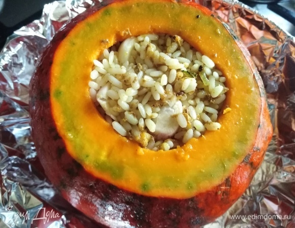 Сверху выложить оставшийся рис, 3 зубчика чеснока. Полить жидкостью, которая осталась от тушения мяса. Тыкву накрыть крышкой и завернуть в фольгу. Поставить в заранее разогретую духовку.