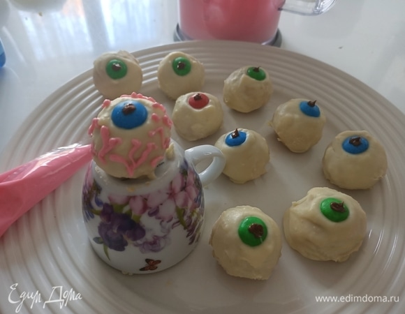 Пока шоколад застывает, делаем цветную глазурь: взбиваем яичный белок, постепенно добавляя сахарную пудру. Когда масса хорошо взобьется, добавляем красный краситель и взбиваем еще немного. Достаем конфеты из холодильника, удаляем излишки шоколада. Перекладываем глазурь в кондитерский мешок и на конфетках рисуем волнистые вены.