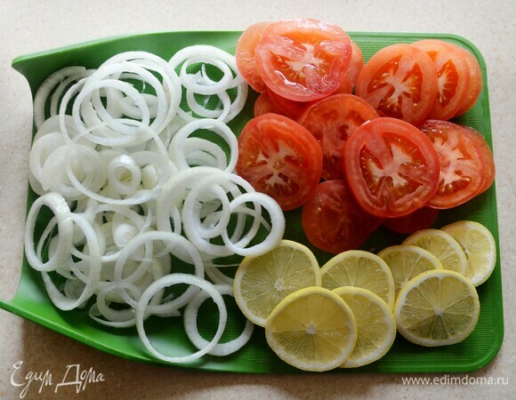 Лук почистить и нарезать тонкими кольцами. Помидоры и лимон вымойте и нарежьте кружочками.